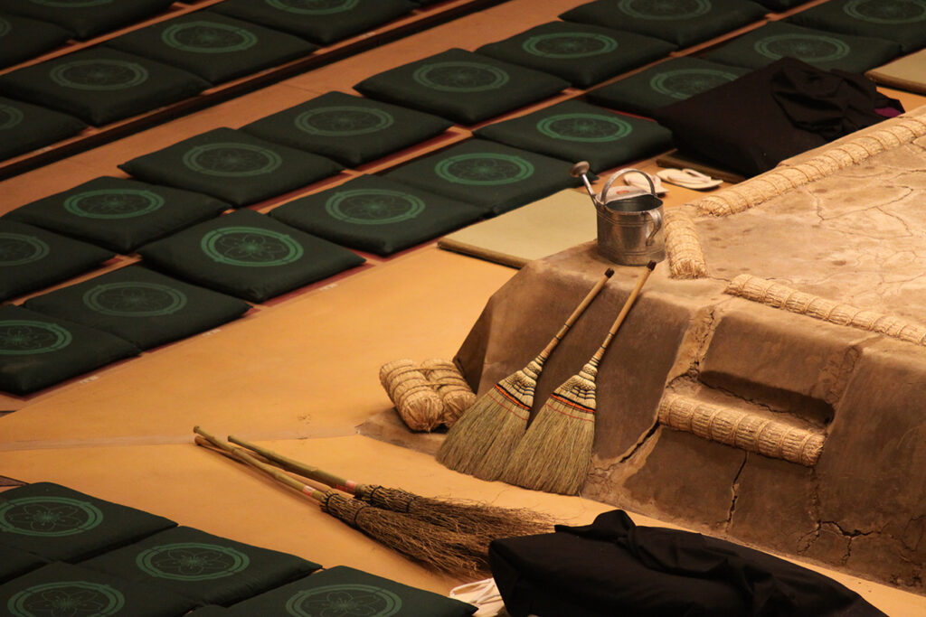 Empty sitting pillows and brooms as equipment next to a fighting ring in a sumo arena in Tokyo, Japan